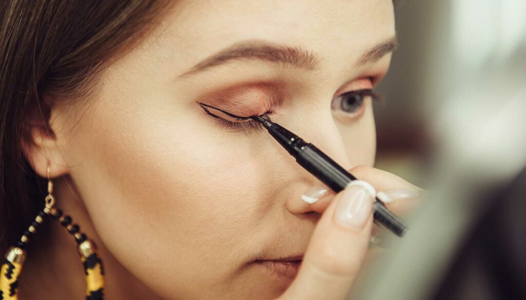 woman applying winged eyeliner, cat-eye