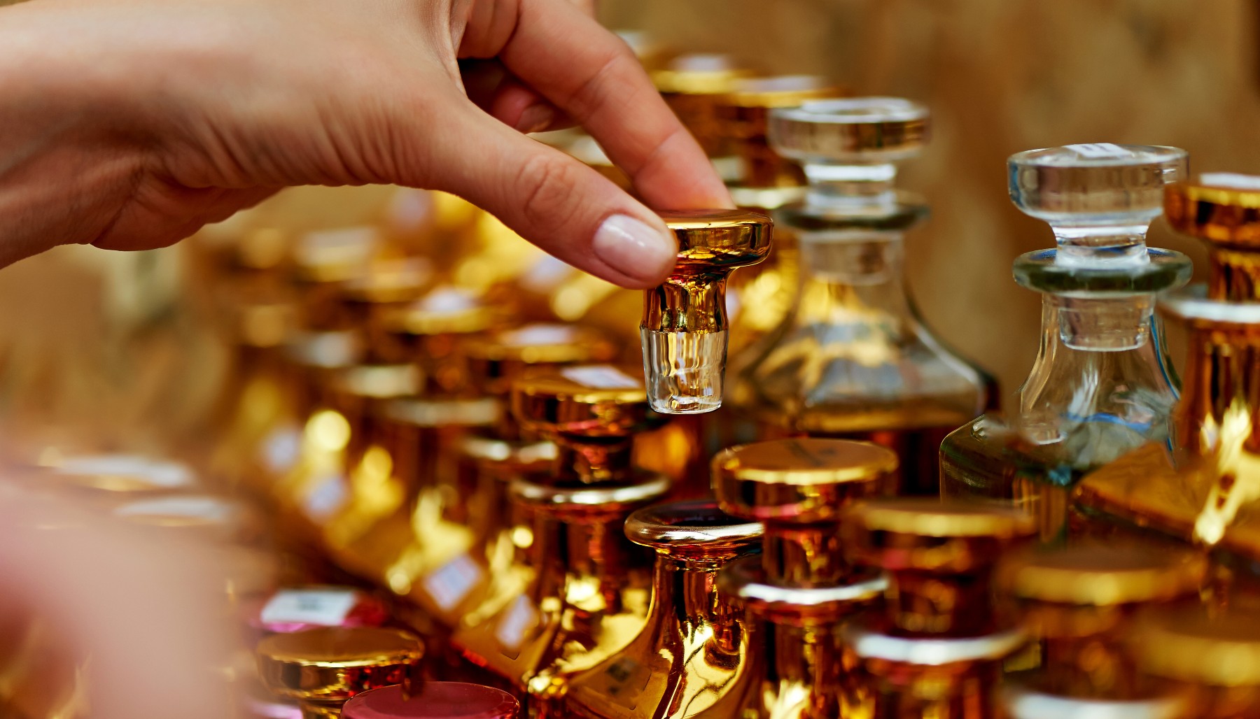 a hand opening a bottle of perfume