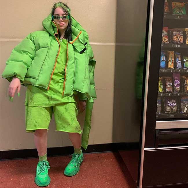 Billie Eilish wearing neon green next to a snack machin