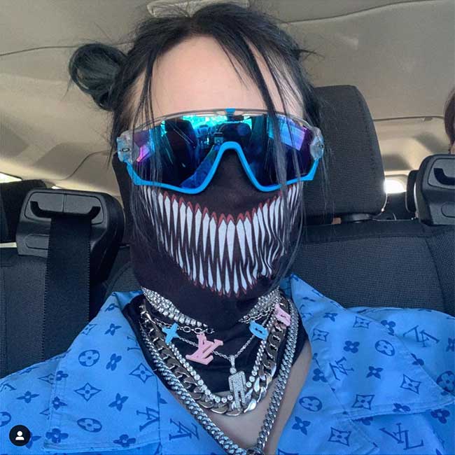 Billie Eilish selfie in the car, wearing sunglasses and a face mask, blue shirt, lots of necklaces