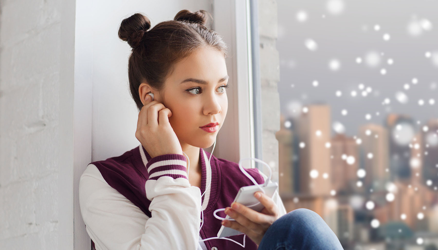 A young woman watching the snow while wearing headphones