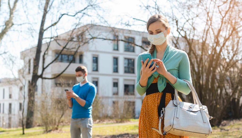 people wearing masks texting each other outside