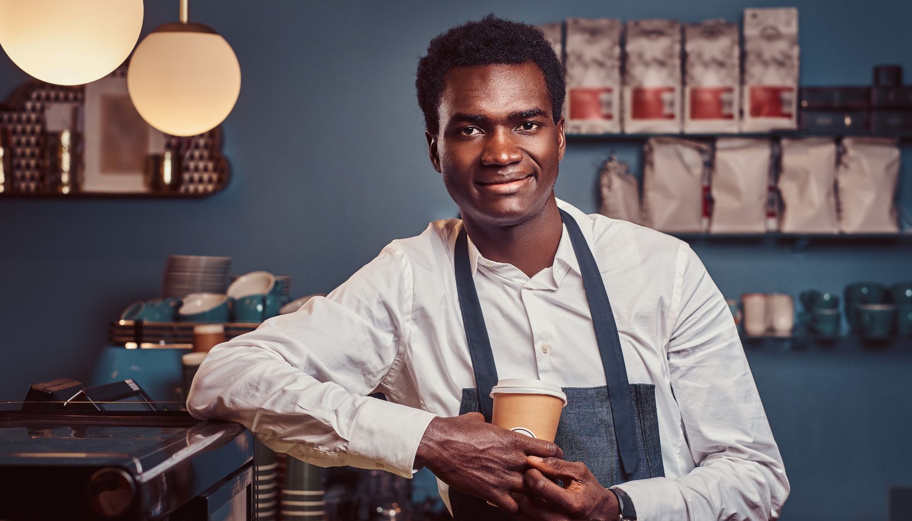 a Black man holding a coffee cup in a coffee shop