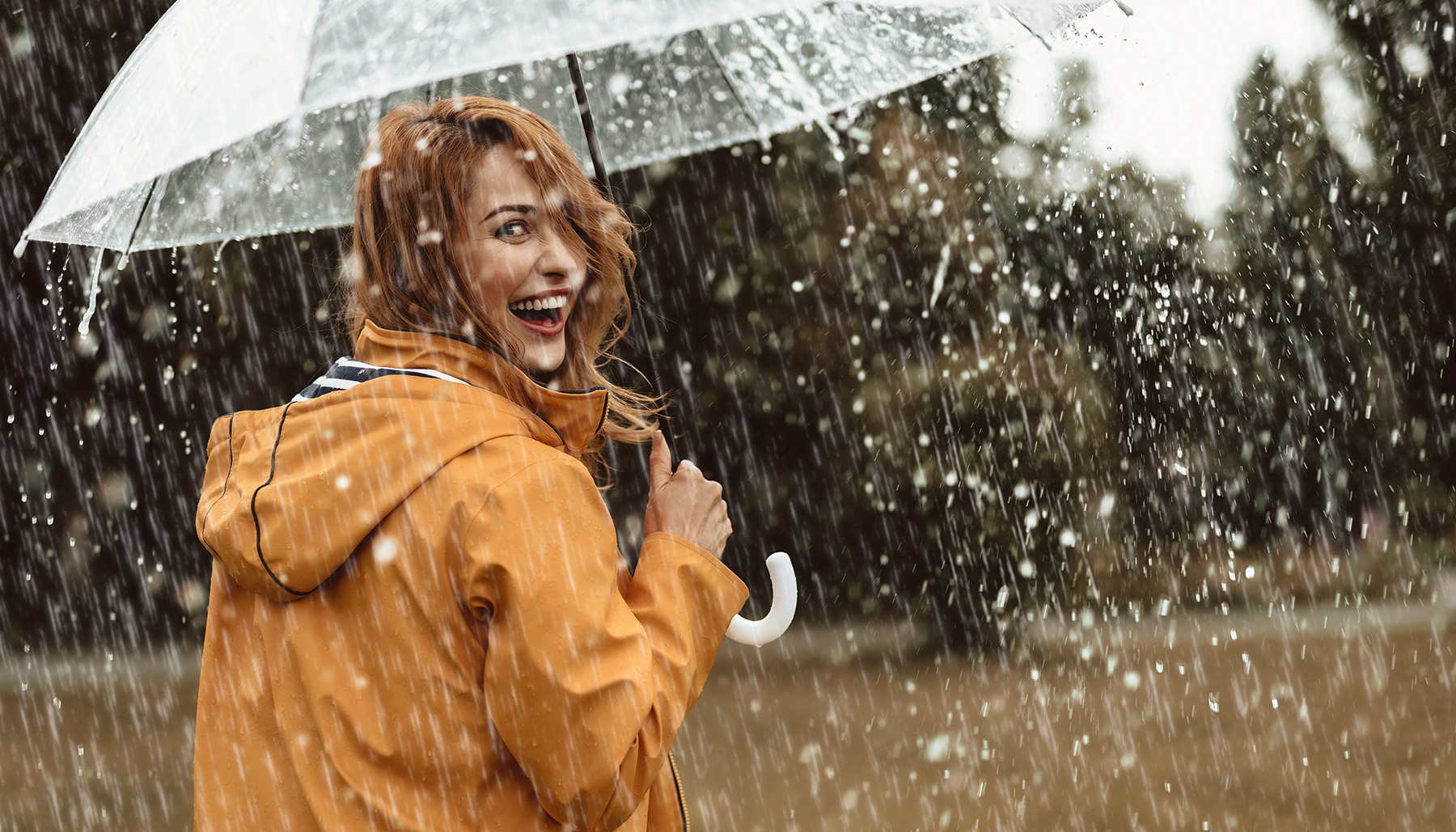 happy-woman-smiles-in-heavy-rain-with-umbrella