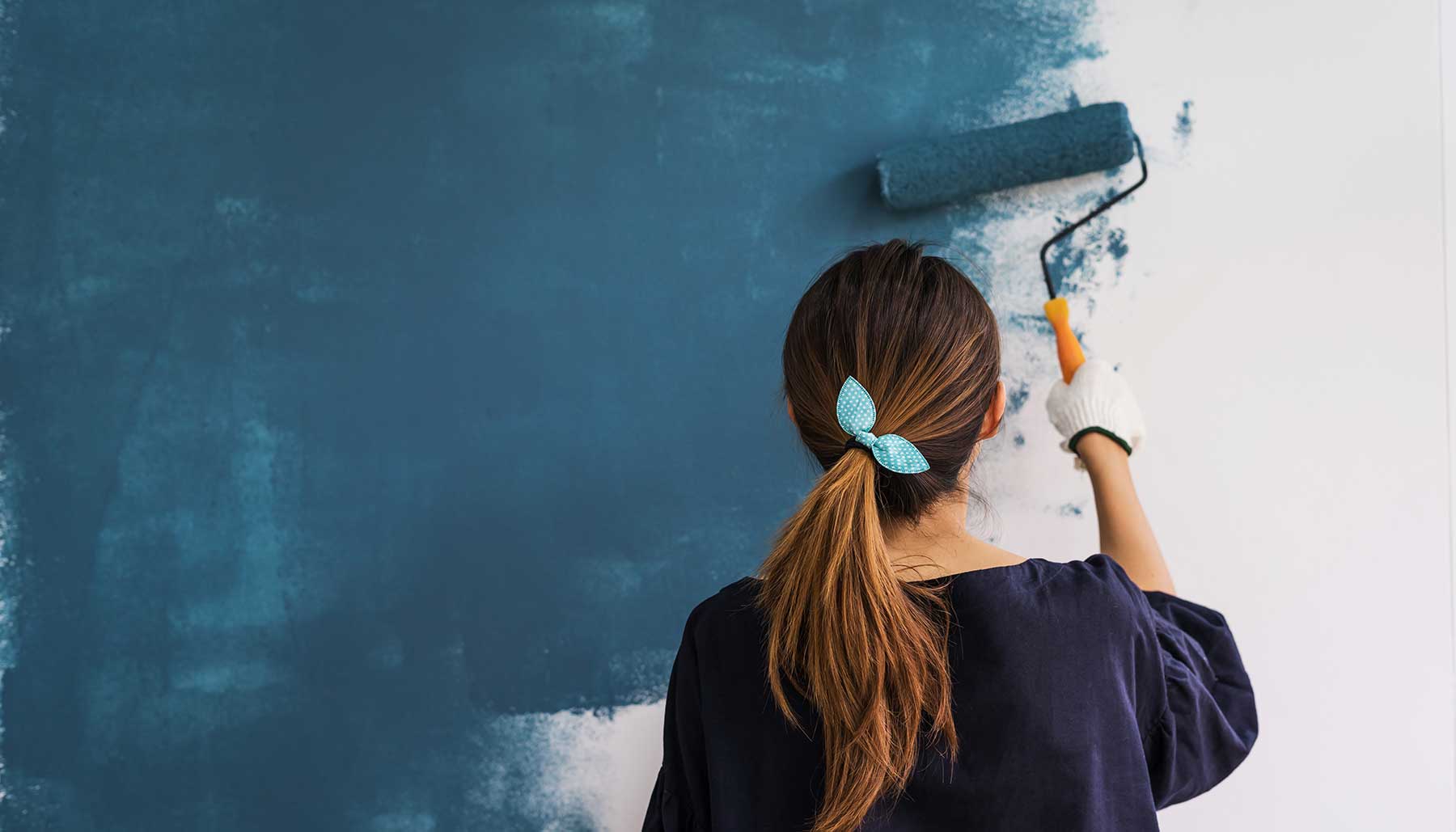 woman painting interior walls blue