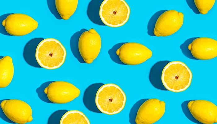 whole and sliced lemons against a bright blue background