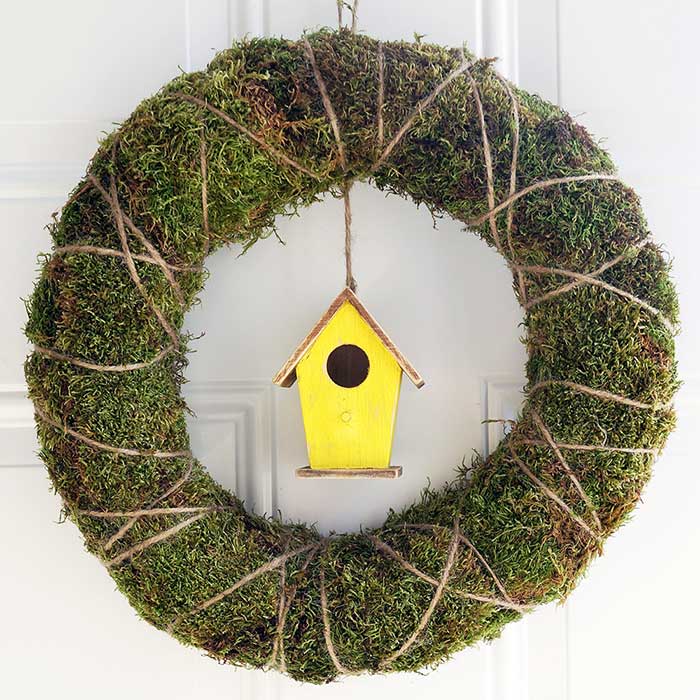 spring wreath made with moss, twine, and a little birdhouse