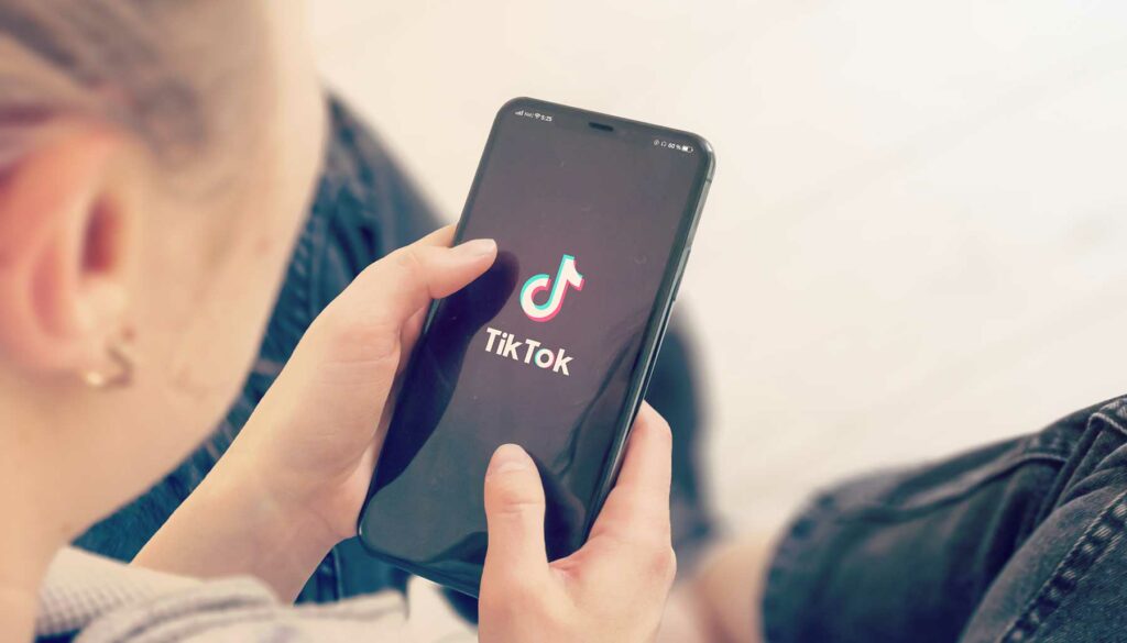 woman holding a phone with TikTok on the screen