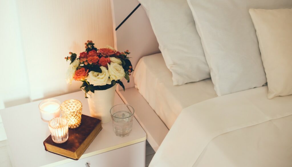 candles and flower next to bed