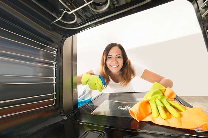 woman cleaning the inside of the oven
