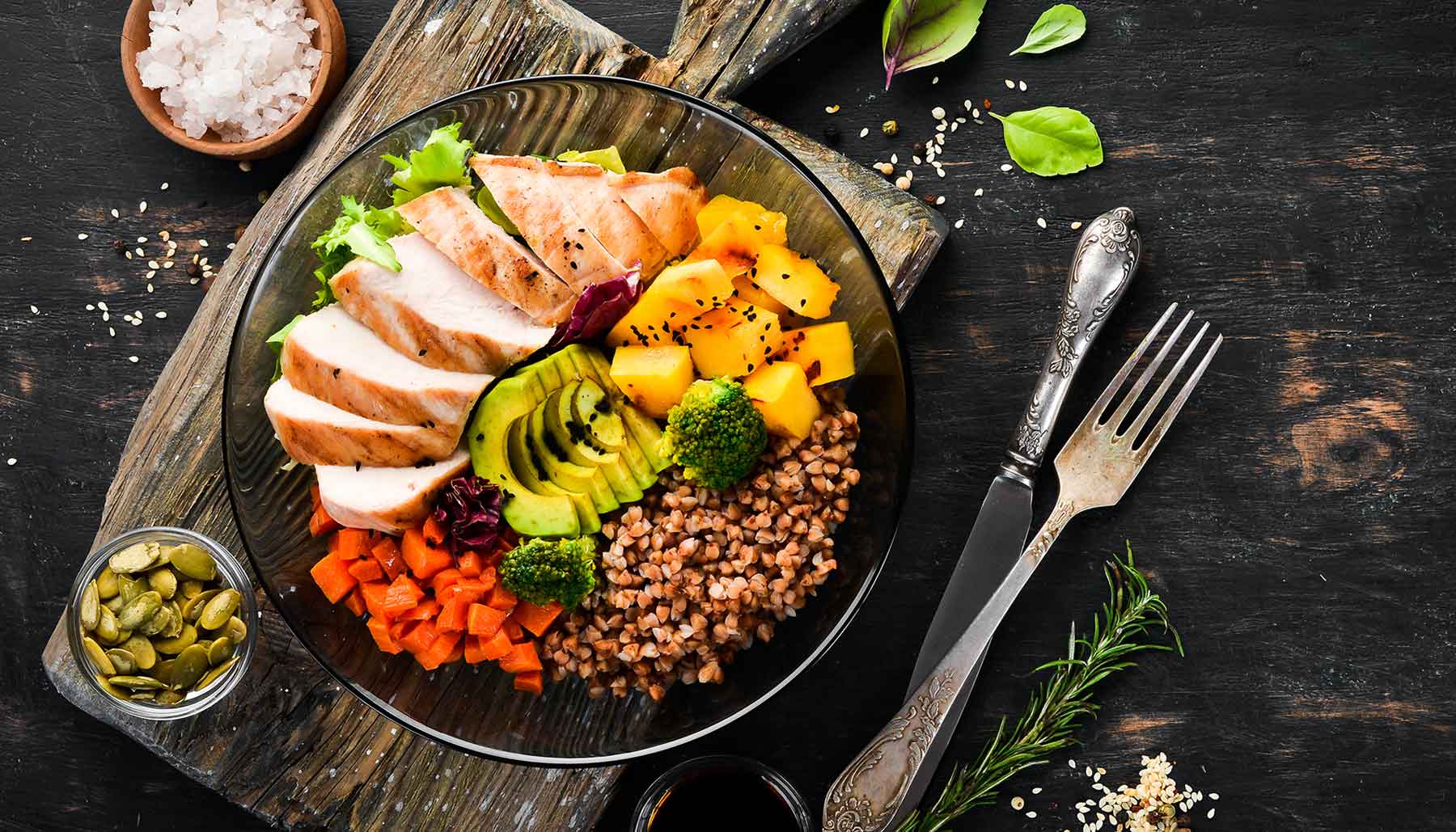 healthy eating, buddha bowl filled with buckwheat, avocado, chicken, carrot, and pumpkin