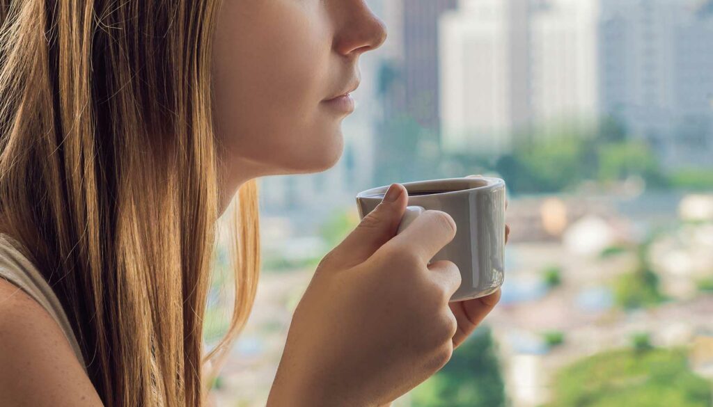 cropped image of a woman drinking coffee on the balcony