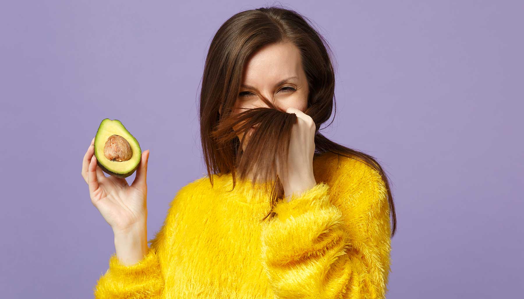 woman with healthy hair holding an avocado, DIY hair masks