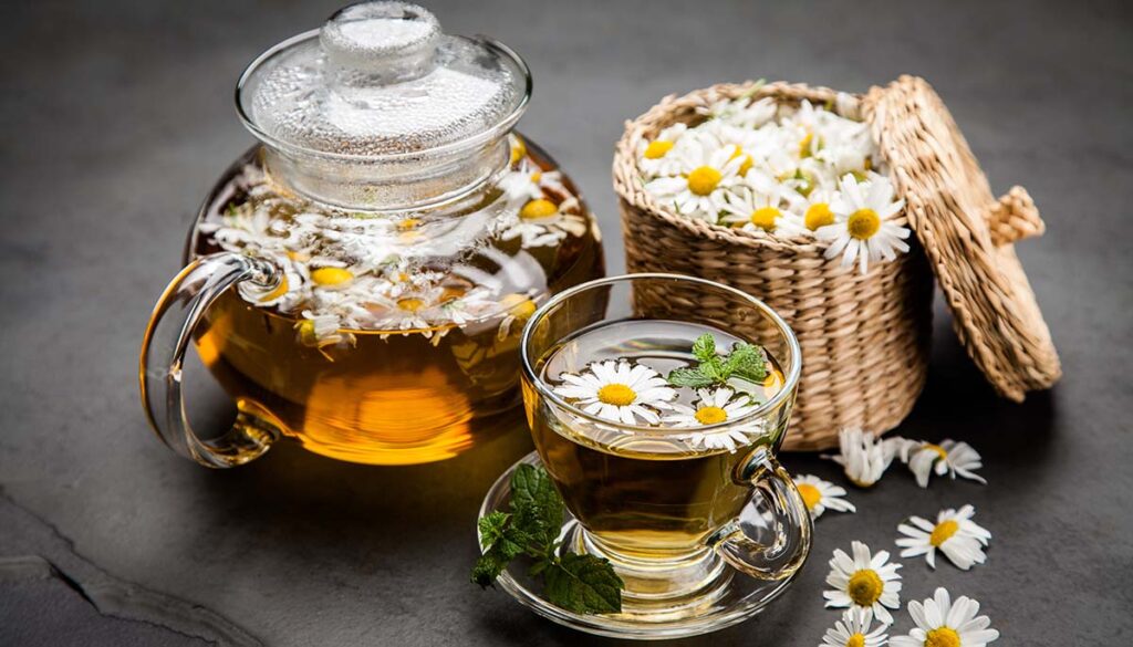 cup and tea pot of chamomile tea and flowers 