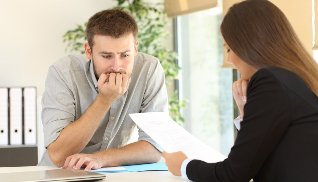 man sitting uncomfortably in front of female boss