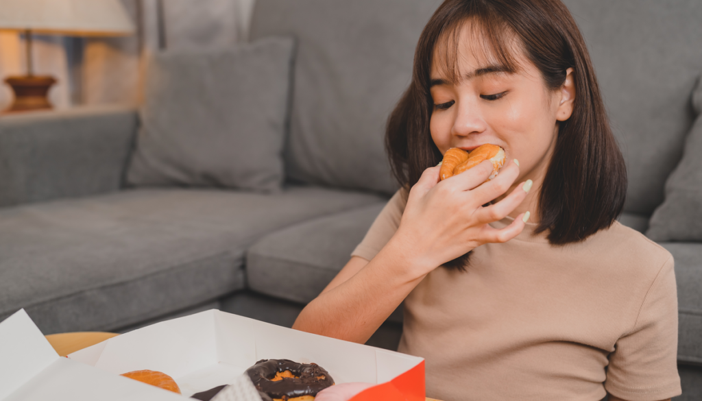 woman sitting down eating donuts out of the box