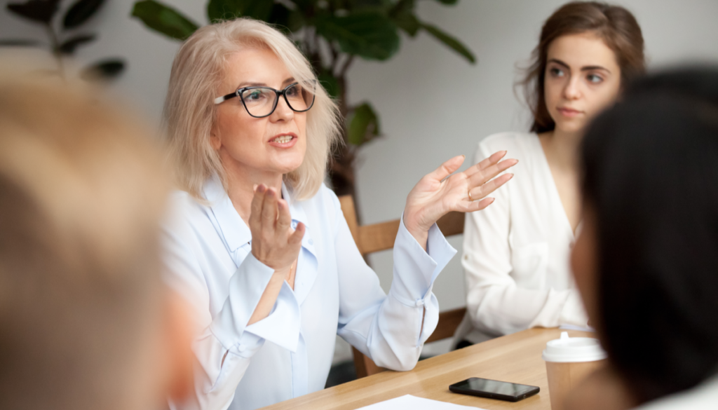 older woman speaking at table with colleagues