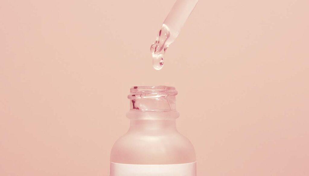 serum dropper and bottle on soft pink background