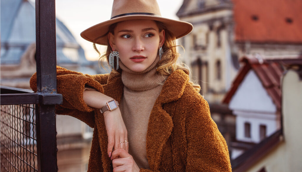 girl in brown shearling coat, turtleneck, and wide-brimmed hat