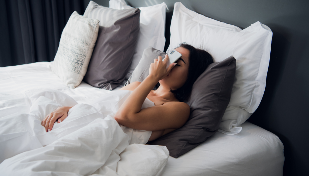 Woman lying in bed pressing phone to face