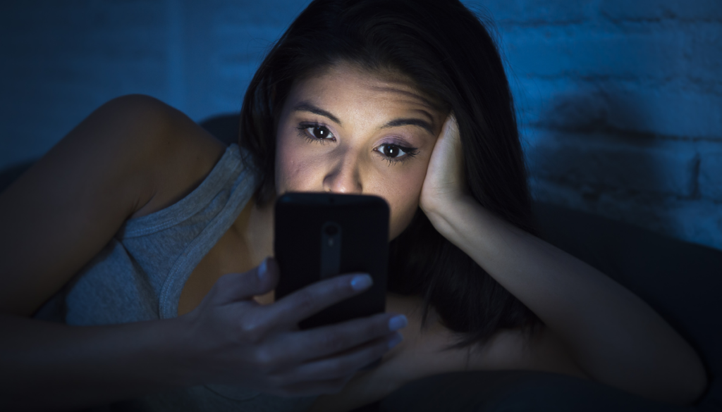 Woman lying in bed looking at her phone