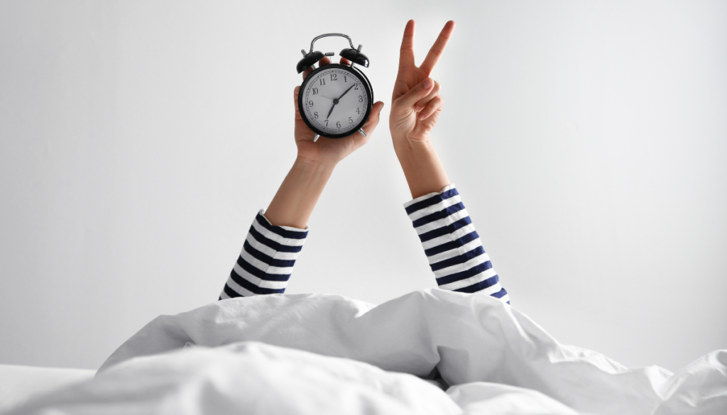 Woman holding up alarm clock in one hand and peace sign in other