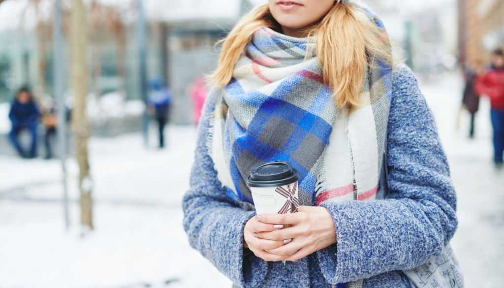 Woman wearing blanket scarf and holding coffee