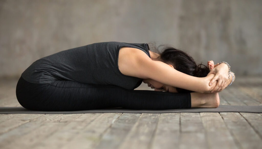 Woman in Yoga Pose Paschimatanasana (Seated Forward Bend)