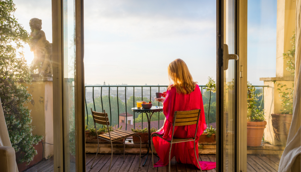 Woman eating breakfast on a balcony in the sun