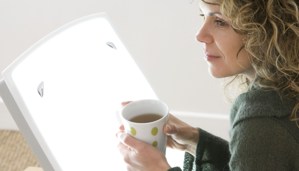 Woman with coffee and light therapy lamp