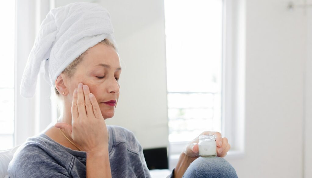 older woman putting cream on face