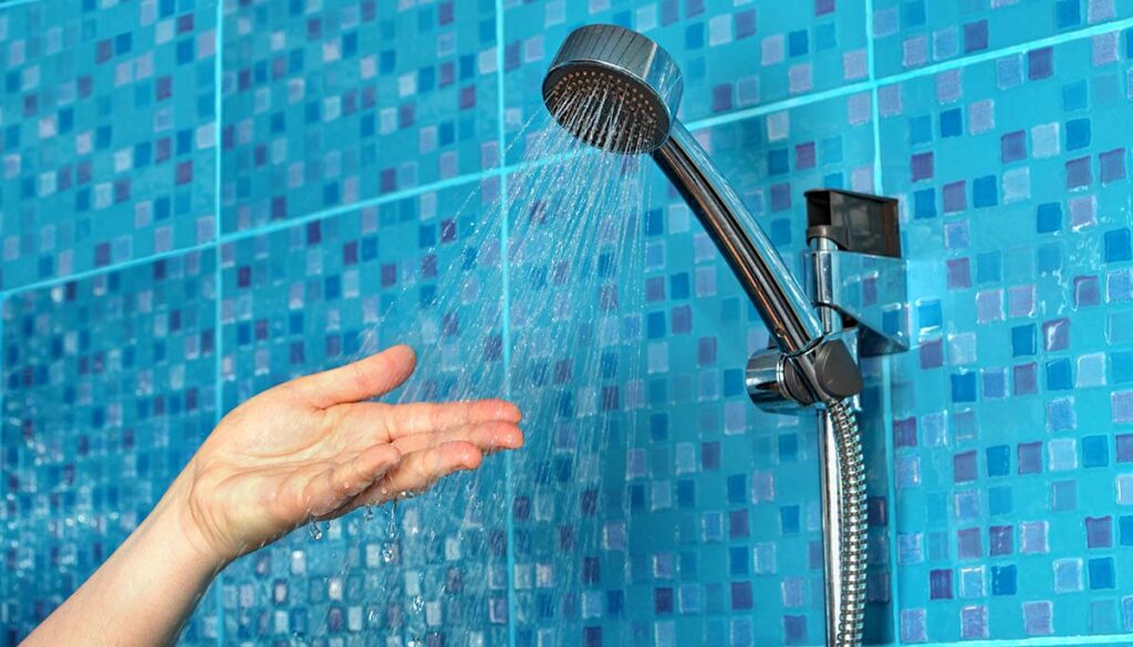 person checking temperature of water from shower head