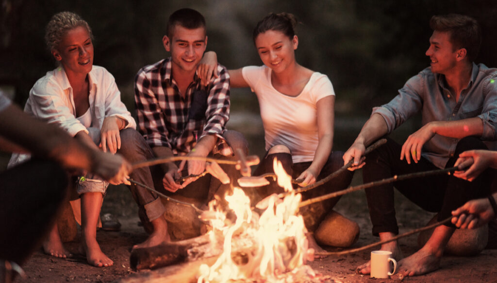group of friends roasting marshmallows at a bonfire
