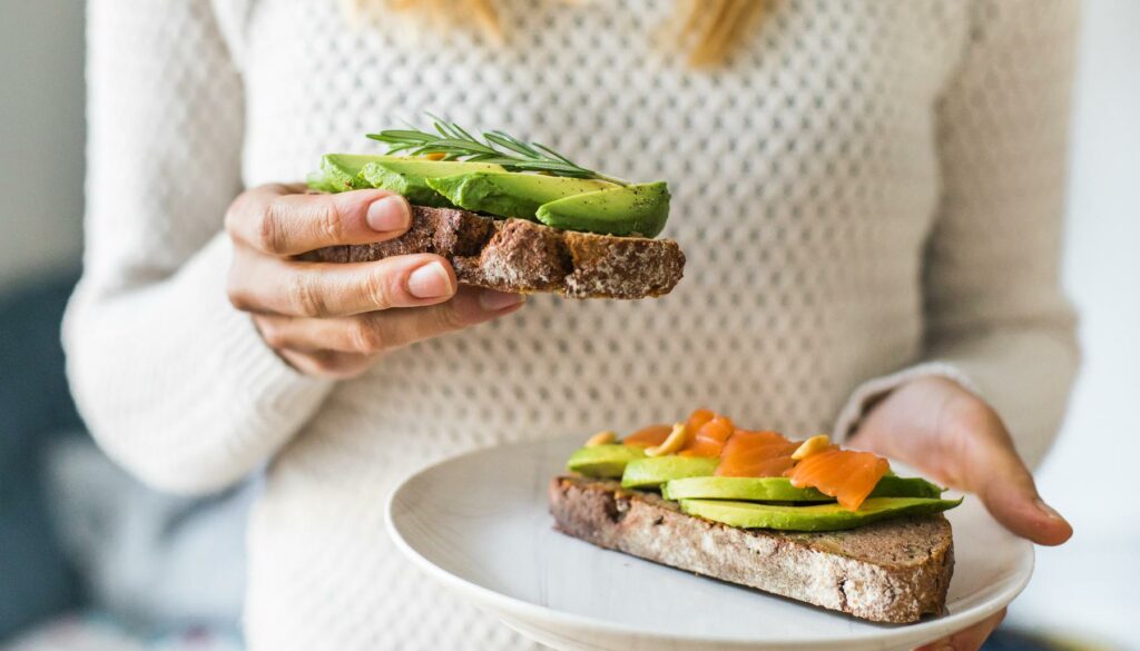 woman holding avocado toast on plate