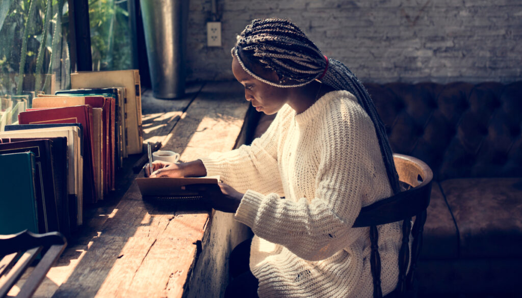 woman sitting/writing at desk with journal