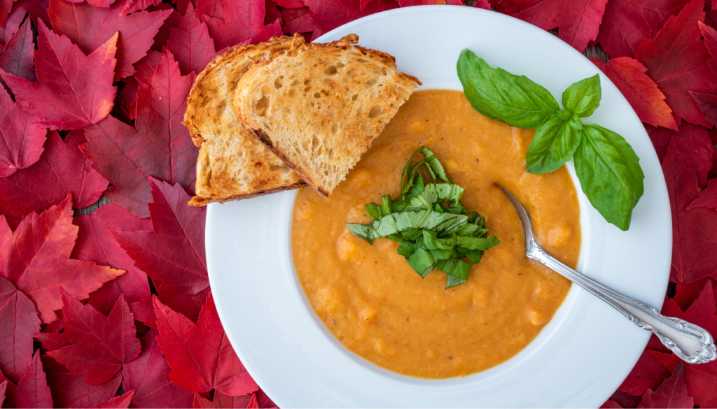 Bowl of butternut squash bisque on top of fall leaves