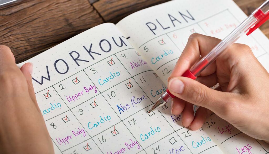 person writing out a workout plan in an agenda