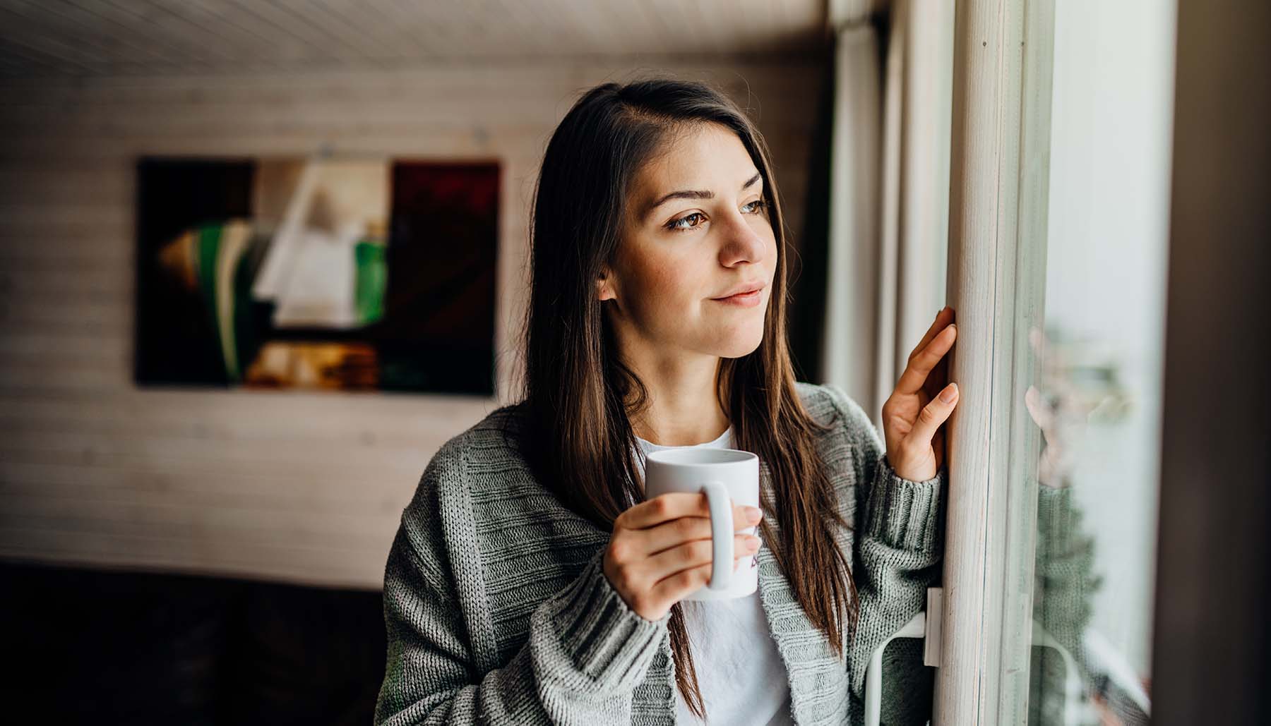 Young woman spending free time home looking out the window