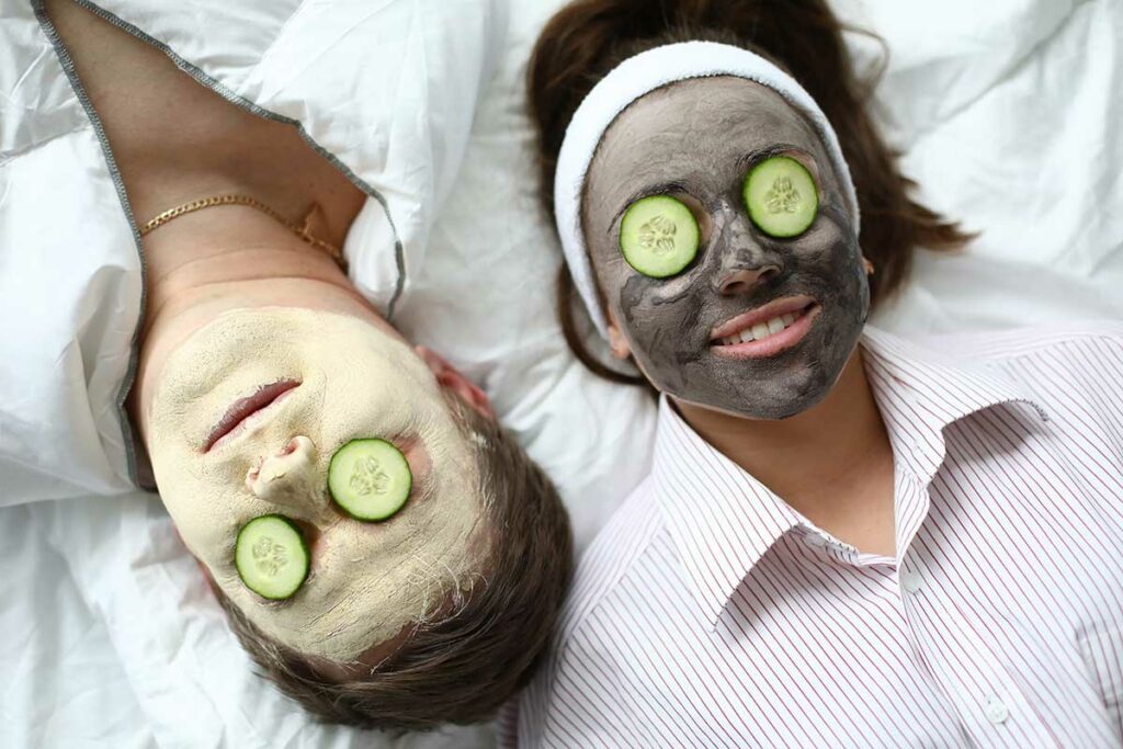couple with mud masks and cucumber slices, spa treatment at home