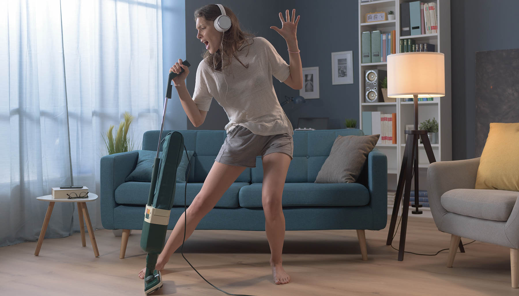Cheerful woman cleaning up her home and singing, she is using the vacuum cleaner as a microphoneCheerful woman cleaning up her home and singing, she is using the vacuum cleaner as a microphone