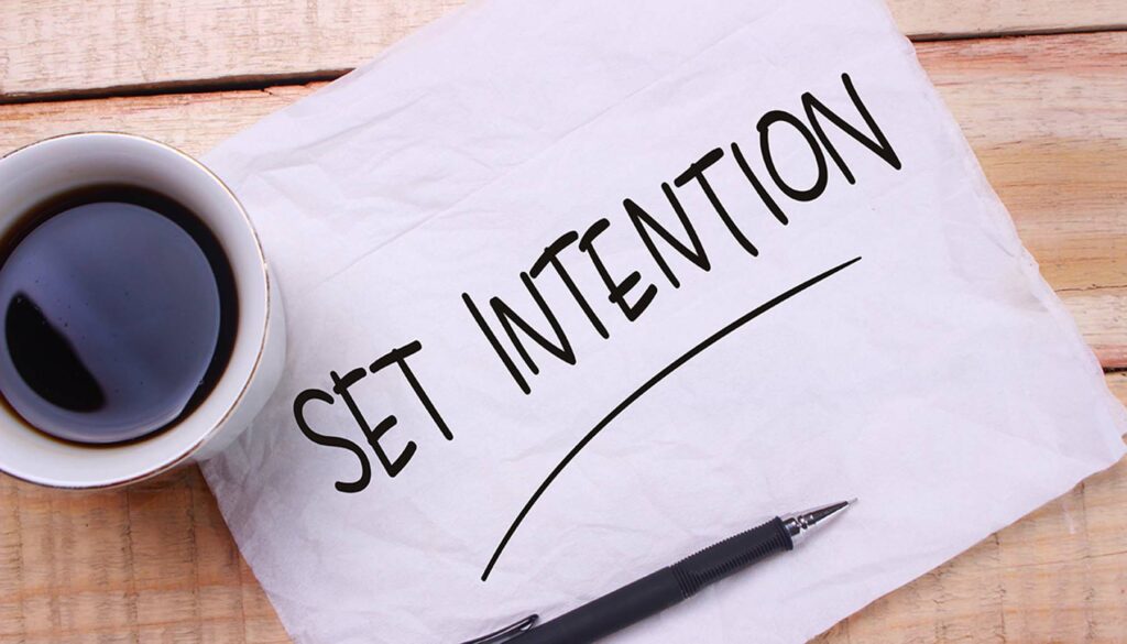 paper that reads "set intention" underlined and cup of black coffee on wooden background