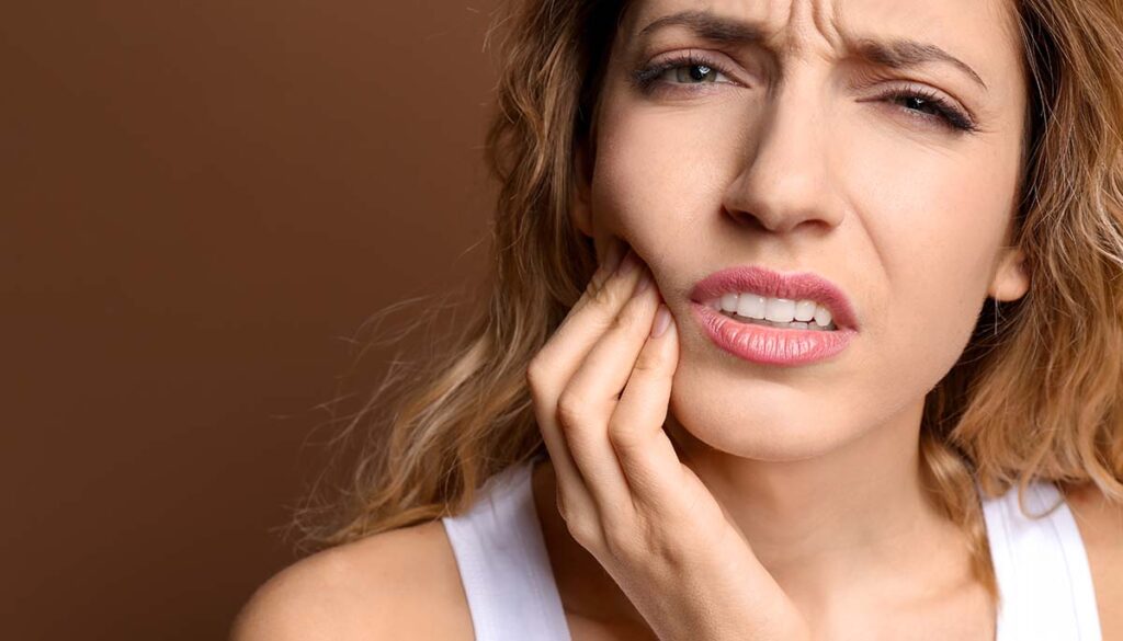 woman holding her jaw in pain and confusion