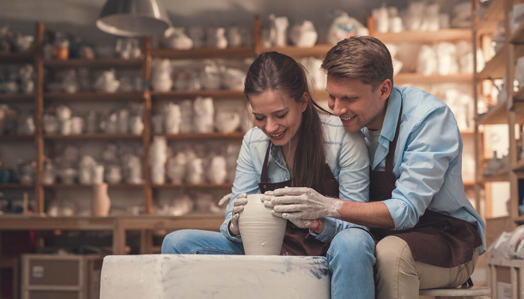 Couple learning to throw pottery