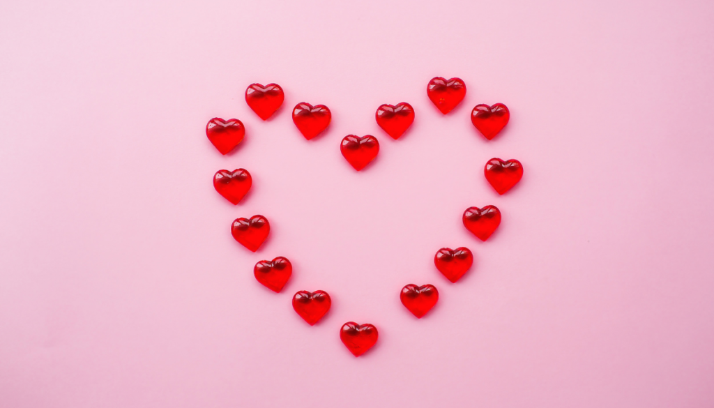 Small red 3d hearts in shape of large heart on pink background