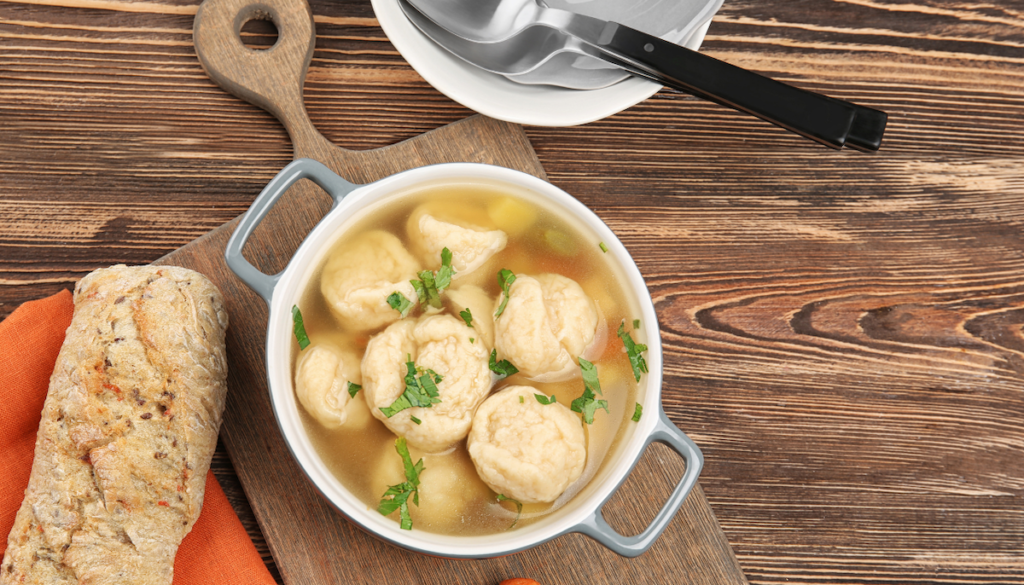 Ceramic pan with delicious chicken and dumplings on wooden cutting board