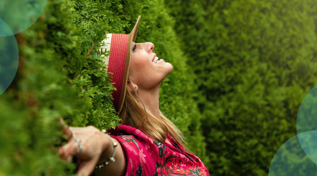 Woman smiling leaning back against hedge