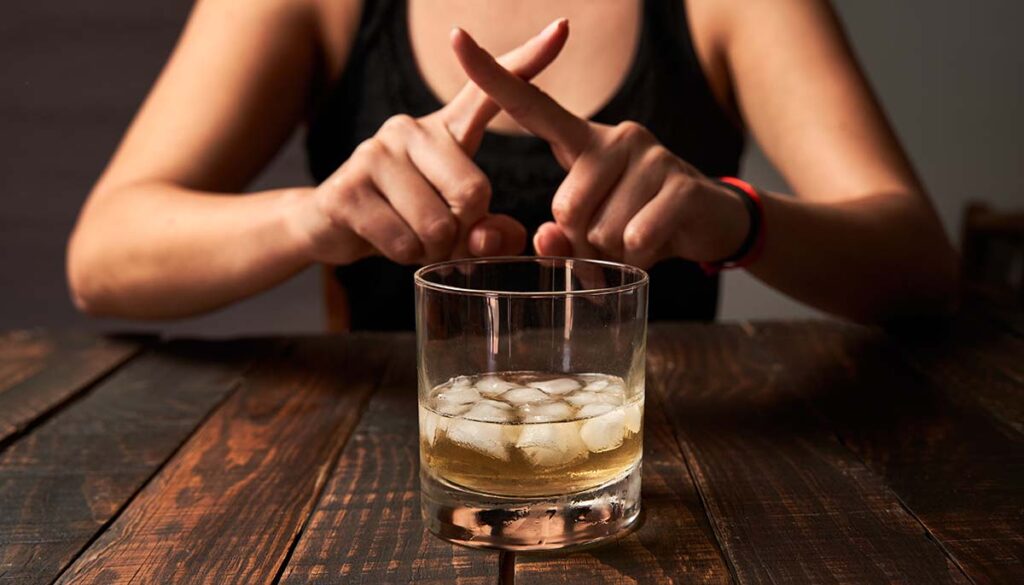 woman saying no to drinking alcohol while making an x with her fingers