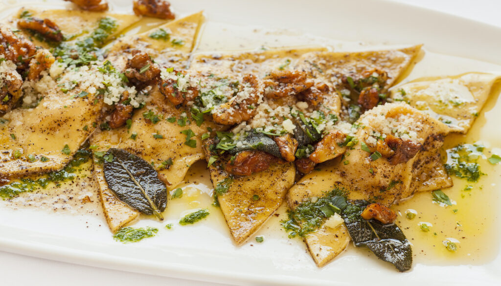 A plate of butternut squash ravioli with sage, brown butter, and walnuts