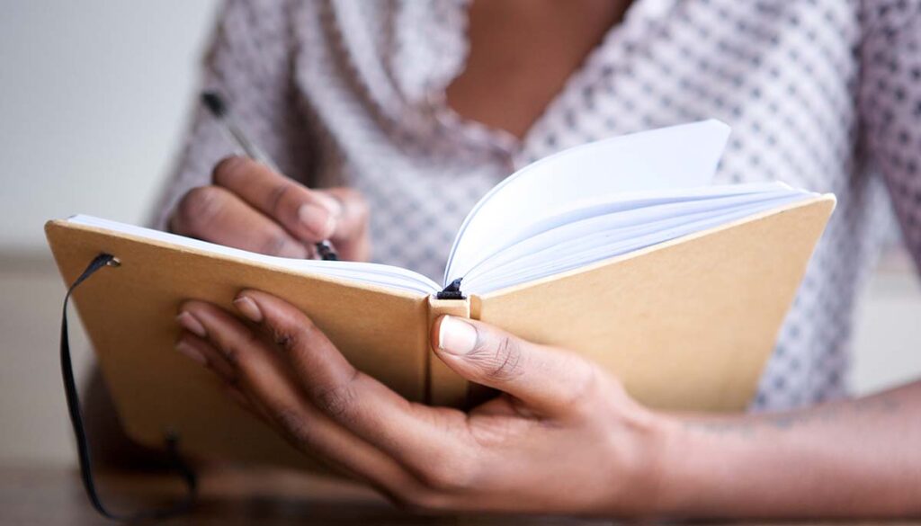close up of woman writing in notebook