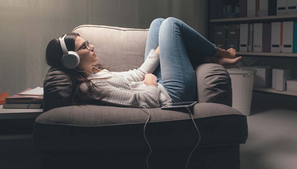 woman relaxing at home with head phones on and eyes closed
